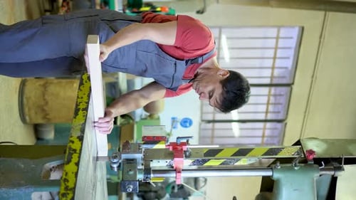 Carpenter Cutting Wood with Band Saw in Workshop