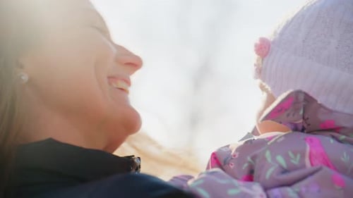 Smiling mother holding her adorable baby outside