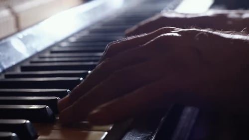 A close-up of a pianist’s hands on an old piano in slow motion.