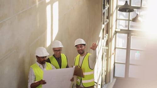 Construction Workers Discussing Blueprints Inside Building