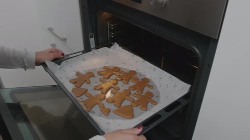 Woman Baking Gingerbread Man Cookies in Oven