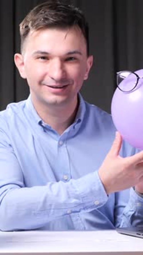 Vertical Video Office Worker Showing Balloon with Glasses at Desk