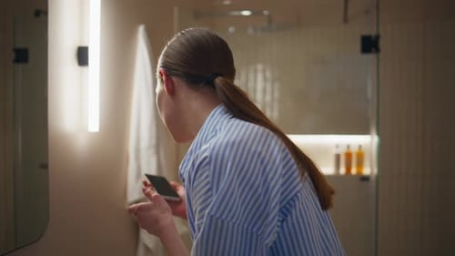 Woman Applies Moisturizer in Modern Bathroom