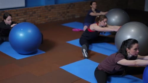 Women Stretch with Exercise Balls in Fitness Studio