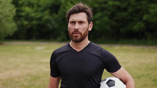 Confident Player Going Through Spacious Meadow and Holding Soccer Ball