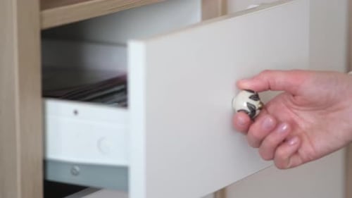 A woman's hand opens a drawer, close-up. Cabinet drawer