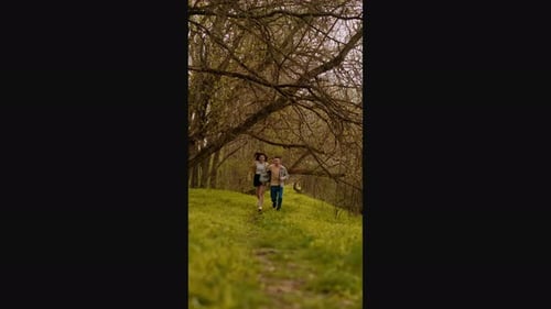 A young couple holding hands run through the forest, embodying an active lifestyle and tourism. Spor