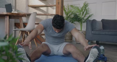 Man Stretching Legs on Yoga Mat at Home