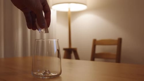 Ice Cube Dropped in Glass on Table