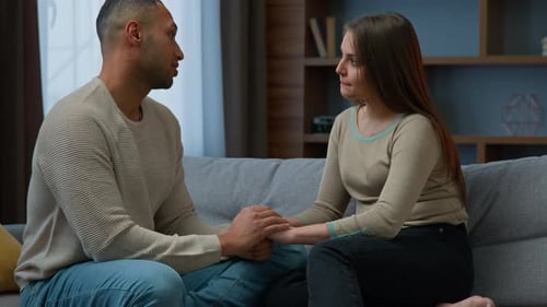 Loving Couple Holding Hands and Talking on Couch