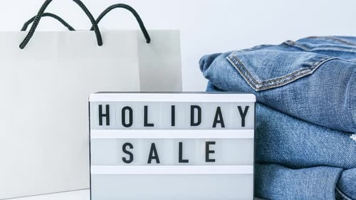 Zoom in Out Light Board with Text HOLIDAY SALE with Paper Shopping Bags Jeans Clothes
