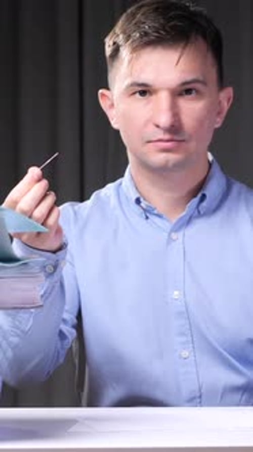 Vertical Video Office Worker Holding a Needle and Balloon Near Stack of Folders
