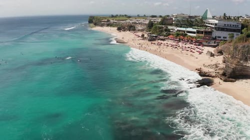 Curva de cámara cinemática de sobrevuelo de un dron para capturar a los surfistas en el océano surfeando en grandes olas, nadando y
