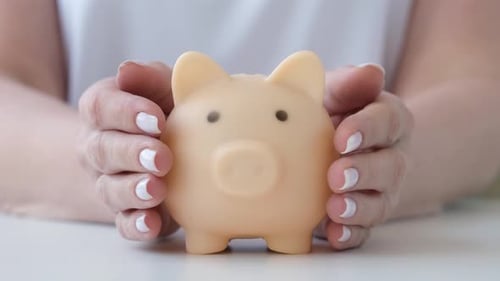 Person Protecting Piggy Bank By Hands Close Up Savings Security