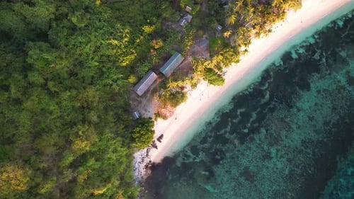 4K drone video looking down on a white sand beach and crystal clear turquoise water near a tropical