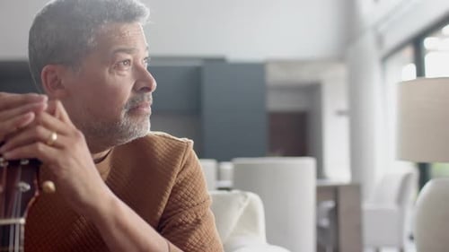 Man Holding a Guitar in a Home