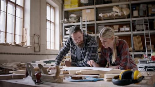 Carpenters discussing product design inside a bright woodworking workshop