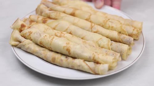 close up shot of hand holding a plate of Delicious homemade crepes on a white plate ready to serve