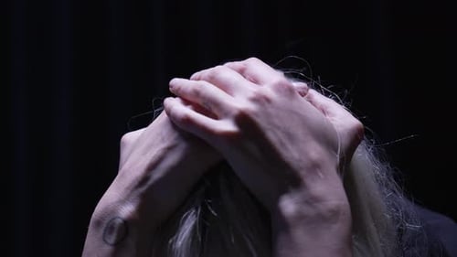 Woman's Hands on Head in Dark Setting