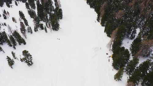Aerial drone flight tracking skier skiing down the snowy mountain during wintertime in Italy. Active