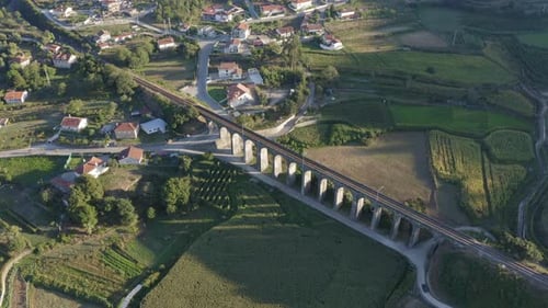 Aerial shot circling around (orbit) Old arch railway bridge surrounded by crop fields, casting shado