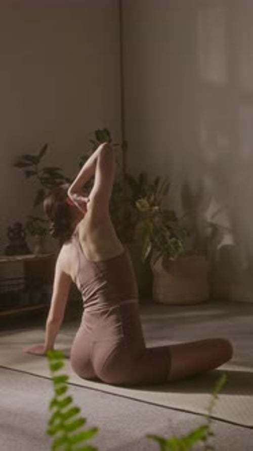 Weibliche Yogaliebhaberin dreht und streckt die Schultern in Lotus-Haltung