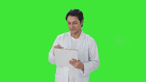 Cheerful Indian scientist writing observations Green screen