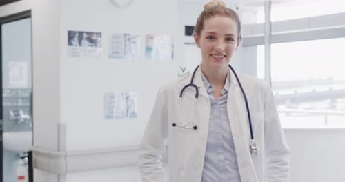 Portrait of happy female doctor with stethoscope smiling in hospital, in slow motion, copy space