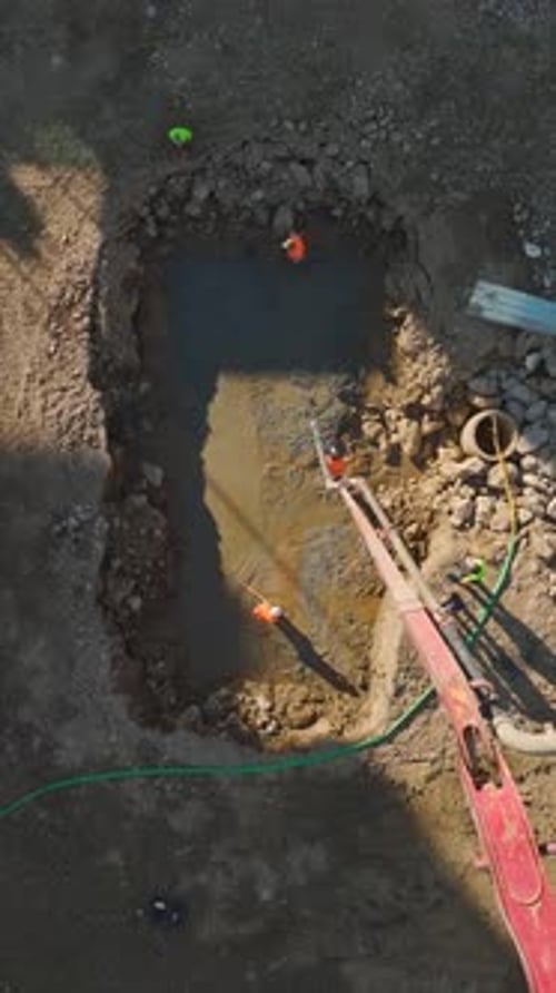 Vídeo vertical: Zona de construcción activa con equipo pesado y trabajadores preparando los cimientos