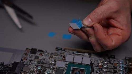 Hands Repairing Graphics Card with Thermal Pad