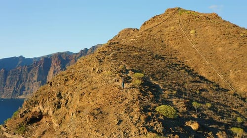 Aerial of a Man Silhouette Climbing Up the Mountain at Amazing Sunset