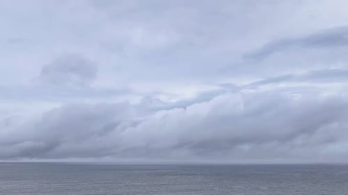 Time lapse of low, racing clouds and fog clearing over the ocean, revealing a distant ship.