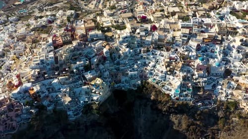 Top down aerial spinning over famous greek village Oia with white cave houses and villas in Santorin