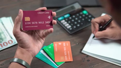 Showing a Man holding a credit card and using a calculator