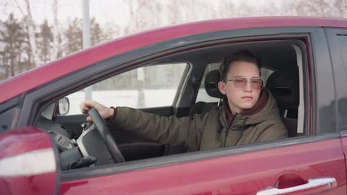 Young Adult Driving Red Car in Winter
