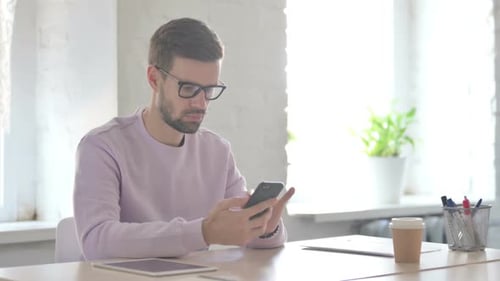 Young Man Using Smartphone in Office