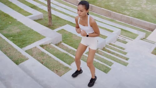 Young fitness woman in sportswear exercising in city park