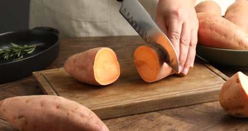 Sweet Potato Being Sliced on Wooden Cutting Board