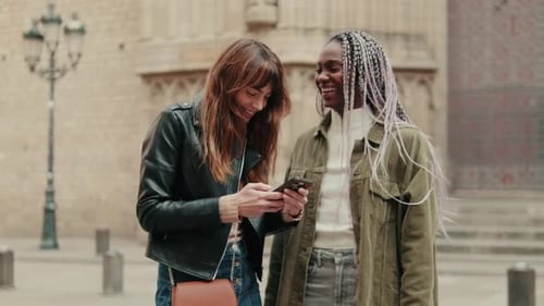 Friends Laughing While Looking at Phone in City