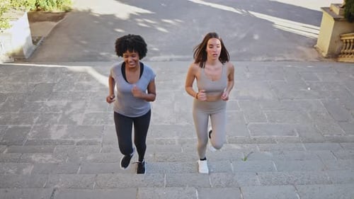 Women Running Up Steps in Urban Environment