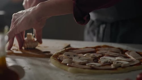 Pizza, Kellner bereitet Essen zu und verteilt am Arbeitsplatz stressig Pilze auf dem vorbereiteten Teig