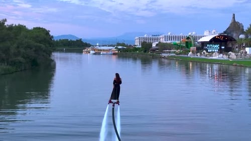 Aerial View Adventurous Girl Flyboarding Over River at Sunset