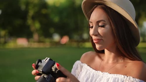 A Young Woman is Enjoying the Art of Photography While Relaxing in a Beautiful Park Setting