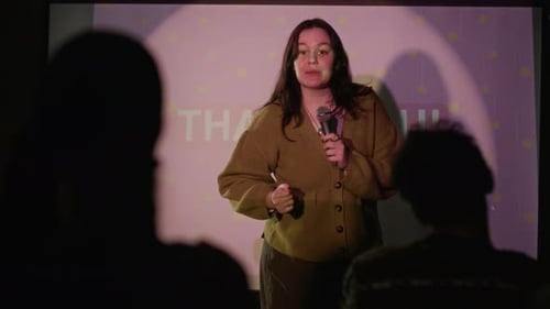 Young Woman Presents With Microphone at Business Conference
