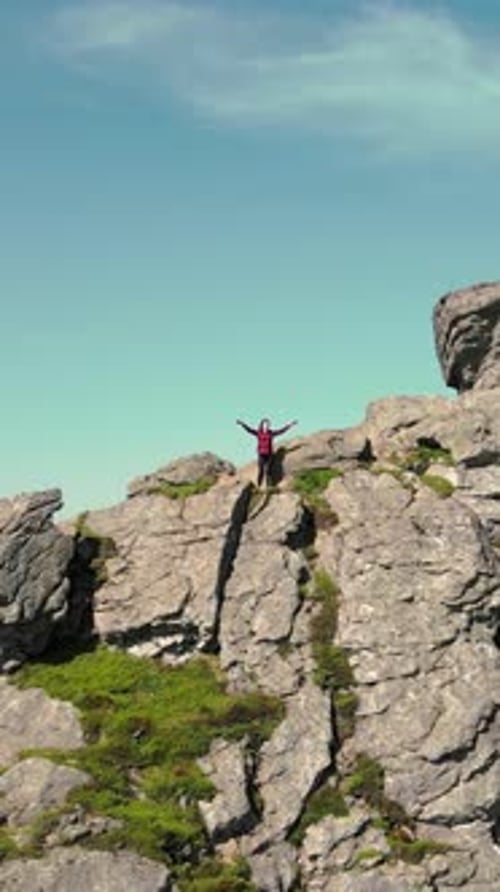 Adult Standing on Mountain Peak with Arms Raised