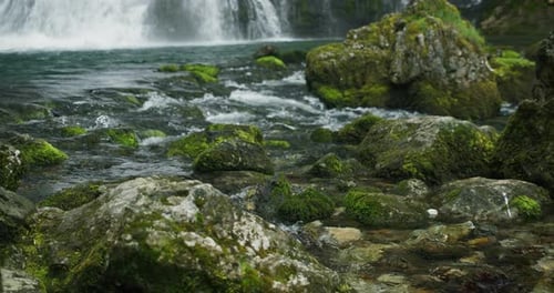 El
río de montaña fluye por la ladera. Agua transparente, haga espuma y salpique en rocas cubiertas
de musgo verde.