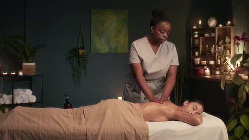 Massagetherapeut führt eine entspannende Rückenmassage an einer Kundin durch