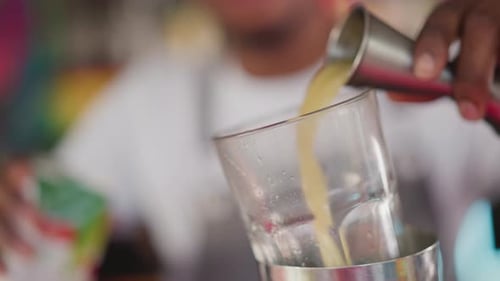 Bartender Pours Juice Into Glass Cup in Bar