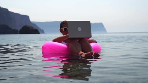 Woman Freelancer Works on Laptop Swimming in Sea on Pink Inflatable Ring Happy Tourist in Sunglases