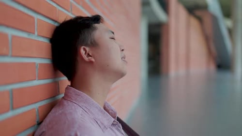 Close-up of Asian man's face sitting with a very disappointed and sad expression,